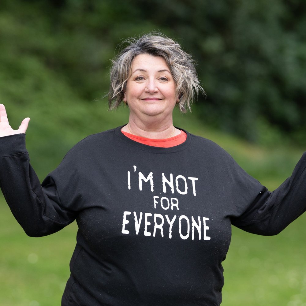 Rachel Atkinson smiling with her arms raised, wearing a black sweatshirt printed with the words "I'm not for everyone".